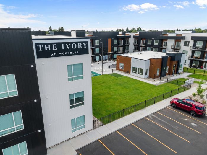 Modern apartment complex 'The Ivory at Woodruff' featuring sleek architecture, spacious green lawn, and convenient parking.