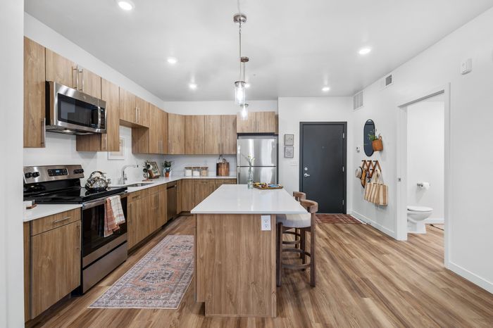 Modern kitchen boasting sleek stainless steel appliances, elegant wooden cabinets, and a spacious island with contemporary seating.