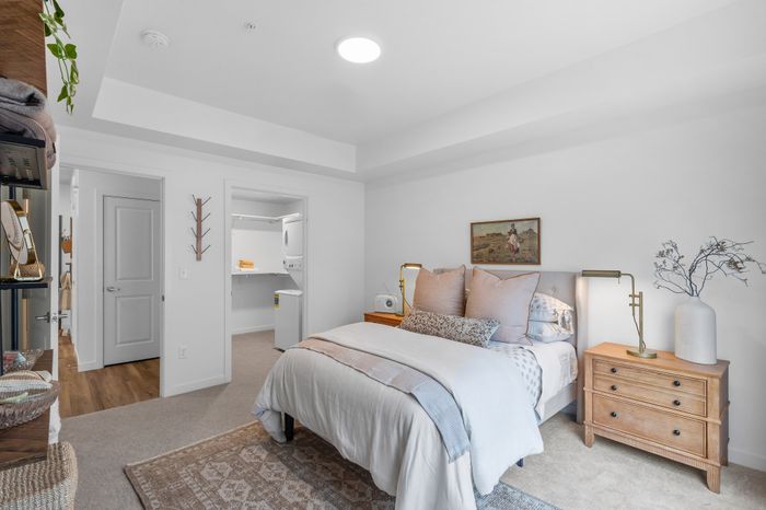 Inviting bedroom with cozy bedding, stylish bedside tables, and a chic decor, leading to a convenient in-unit laundry space.