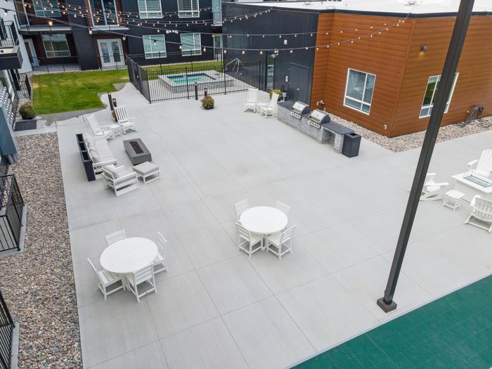 Modern outdoor courtyard featuring stylish seating areas, a fire pit, and a barbecue station under charming string lights.