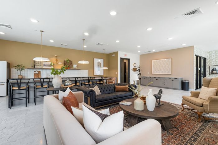 Inviting open-plan living space featuring a modern kitchen with chic bar seating, elegant sofas, and stylish decor in a warmly lit atmosphere.
