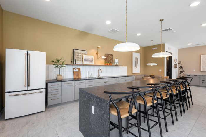 Modern kitchen with sleek gray cabinets, elegant island seating, and stylish minimalist decor.