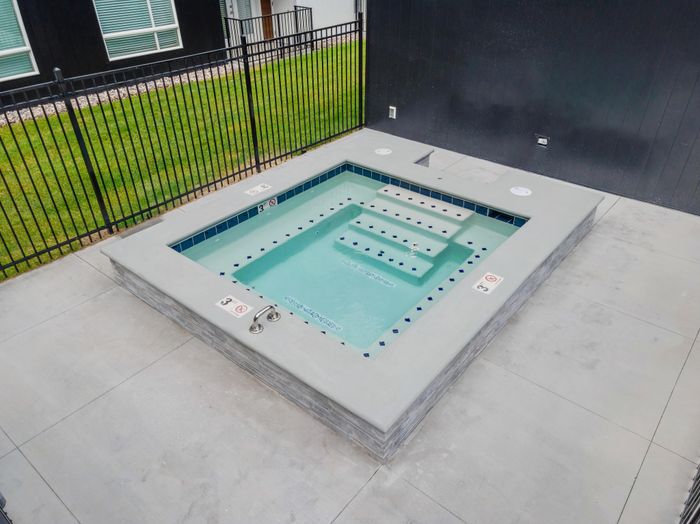 Modern outdoor hot tub with sleek design, enclosed by stylish fencing, perfect for relaxation and luxury living.