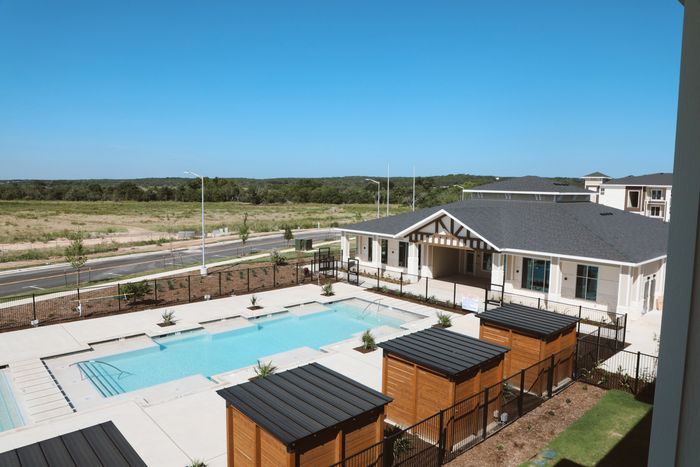 Luxurious apartment complex with a pristine swimming pool, modern wood accents, and scenic views of lush landscapes.