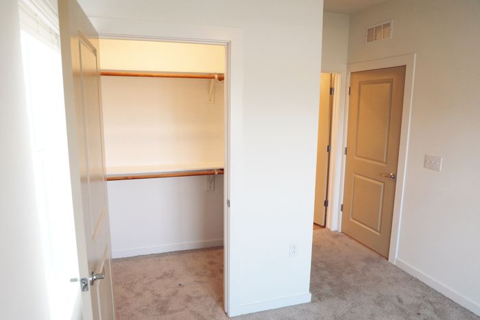 Bright walk-in closet in modern apartment, featuring spacious shelving and natural light.