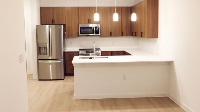 Open-concept kitchen with pendant lighting and a quartz breakfast bar overlooking the living area