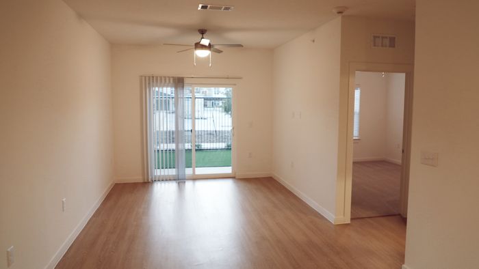 Bright living room with wood-style plank flooring and a sliding glass door to a private patio