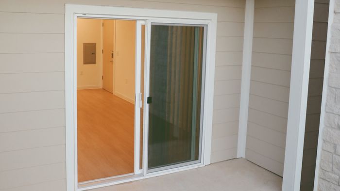 Covered ground-floor patio with a sliding glass door and a balcony overhead