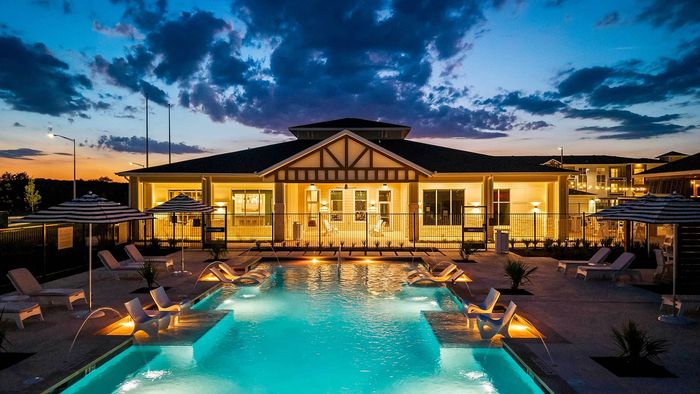 Twilight view of illuminated resort-style swimming pool, sunken sun shelves, lounge chairs, and clubhouse at Entrada at San Marcos.