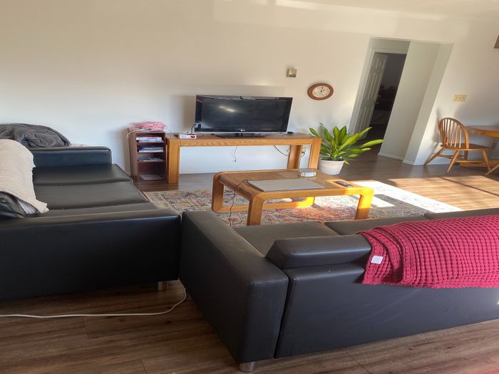 Inviting living room with sleek black sofas, a stylish wooden coffee table, and a TV stand with decor accents.