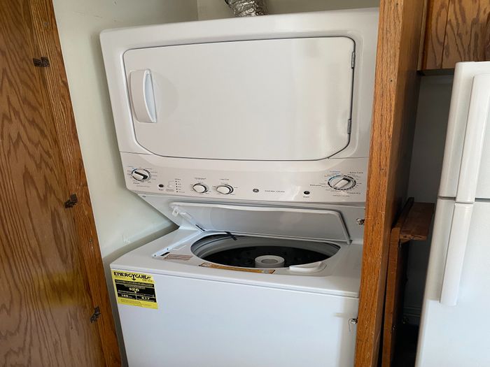 Efficient stackable washer and dryer unit nestled in a wooden closet space.