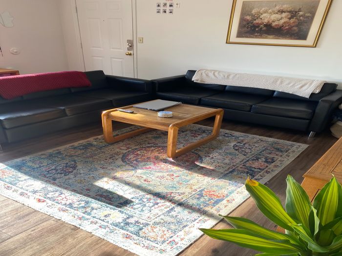 Inviting living room with black leather sofas, a wooden coffee table, and an elegant floral painting.