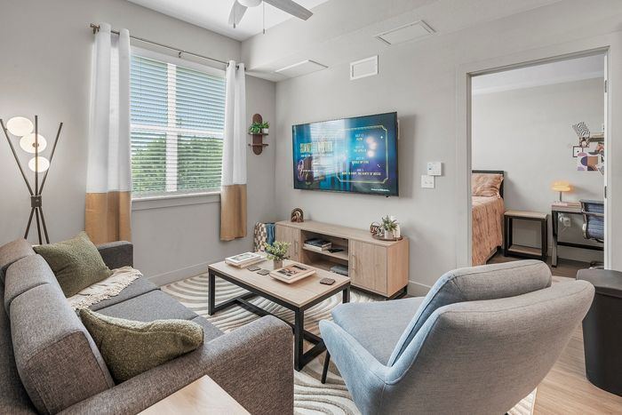 Chic living area with stylish furniture, modern decor, and flat-screen TV, adjacent to a cozy bedroom, perfect for urban living.