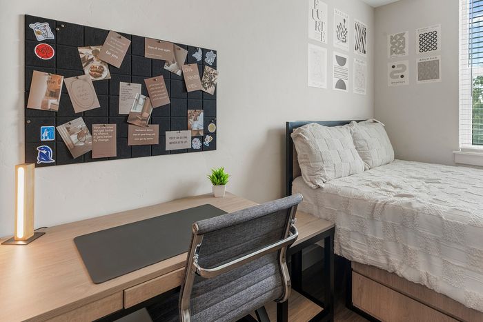 Inviting bedroom with stylish workspace, cozy bed, and inspirational decor, perfect for productivity and relaxation.