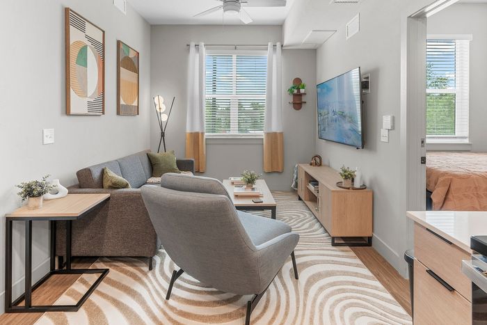 Modern living room with stylish decor, cozy gray sofa, abstract art, and large wall-mounted TV, offering a comfortable and inviting space.