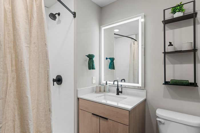 Modern bathroom featuring a sleek vanity with illuminated mirror and elegant shower design.