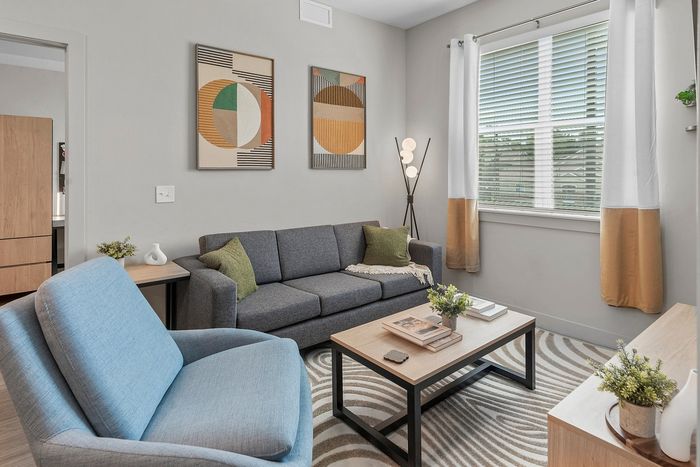 Inviting modern living room featuring a cozy gray sofa, stylish blue chair, and elegant artwork in a bright, airy space.