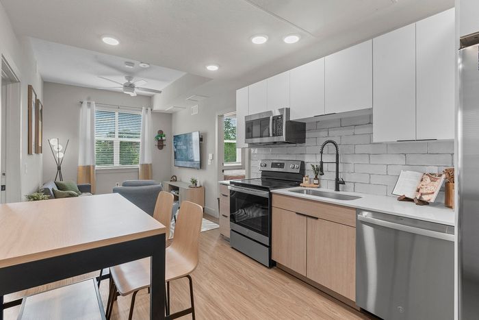 Modern open-concept kitchen and living area with sleek cabinetry, stainless steel appliances, and large windows for natural light.