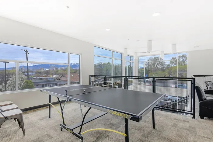 Bright and modern recreation room featuring a ping pong table with stunning mountain views through floor-to-ceiling windows.