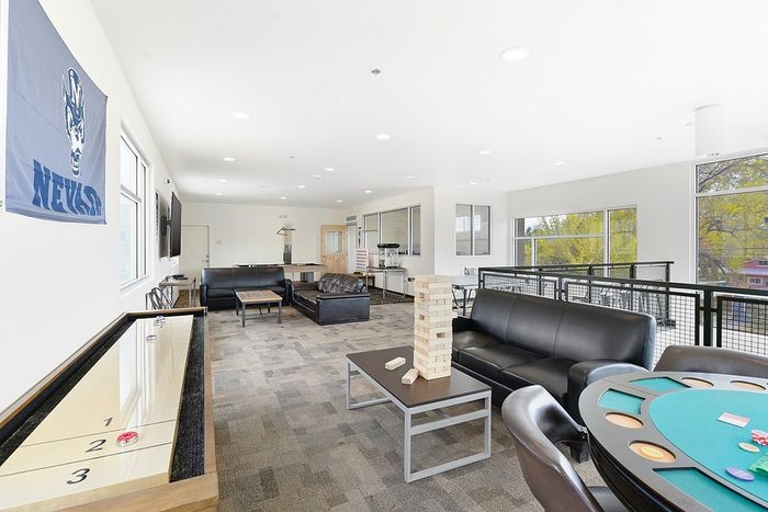 Spacious recreational room with modern seating, game tables, and plenty of natural light, ideal for social gatherings and relaxation.