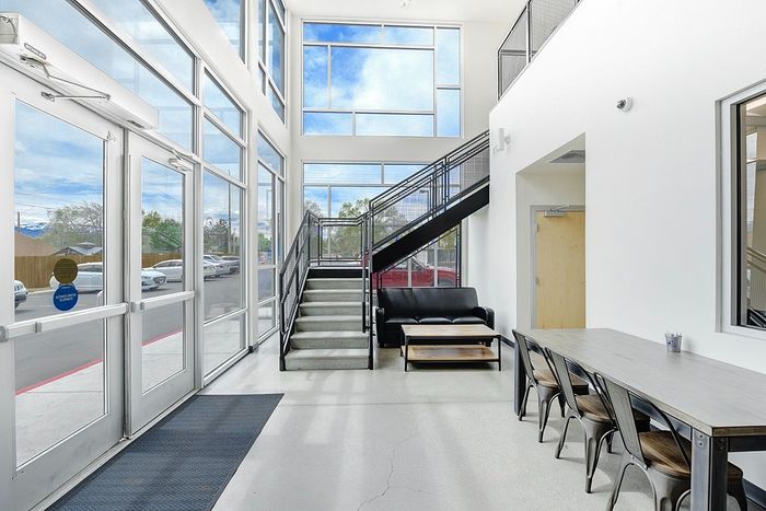 Modern lobby with floor-to-ceiling windows, inviting seating area, and industrial staircase for a spacious and welcoming entry.