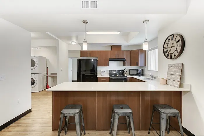 Modern kitchen with sleek countertops, stylish pendant lighting, and dark wood cabinetry, complimented by a cozy breakfast bar and inviting ambiance.