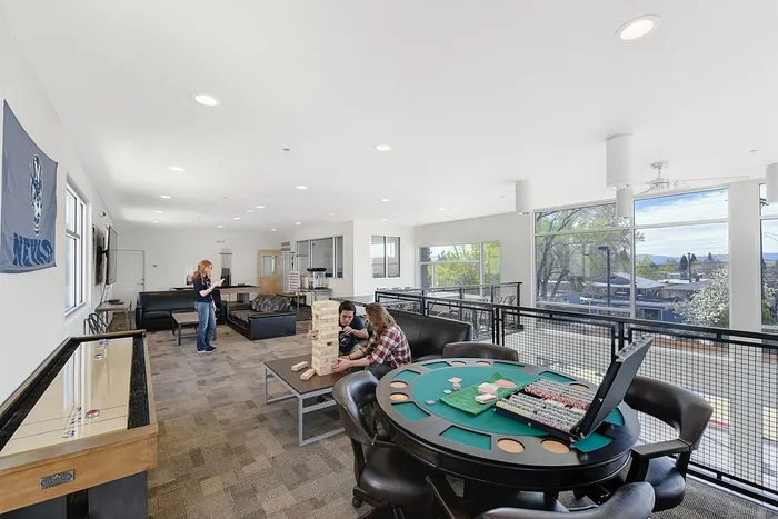 Bright and spacious game room featuring a poker table, Jenga game, and modern lounge area with panoramic views.