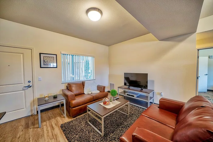 Cozy living room with stylish leather sofas, modern decor, and a flat-screen TV, perfect for relaxation.