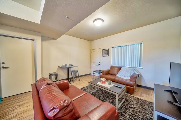 Inviting living room with cozy brown leather sofas and elegant wood flooring, ideal for relaxation and entertaining.