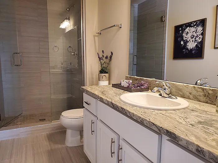 Luxurious bathroom featuring elegant marble countertops, modern fixtures, and a spacious glass-enclosed shower, creating a serene spa-like atmosphere.