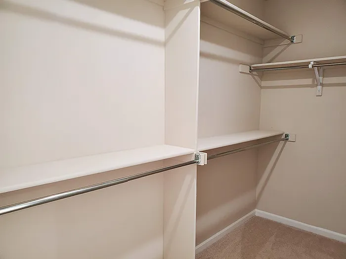 Spacious walk-in closet with multiple shelves and hanging rods, perfect for organized storage.
