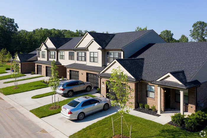 Charming row of modern townhouses with attractive brickwork, lush green lawns, and private driveways, set in a tranquil neighborhood.