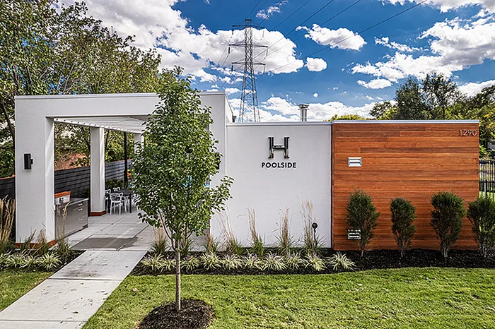 Modern and stylish poolside lounge with sleek design, lush green landscaping, and inviting outdoor seating area.