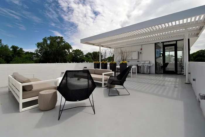 Stunning rooftop terrace featuring modern outdoor seating, lush greenery, and a sleek grill area, perfect for entertaining and relaxing under open skies.