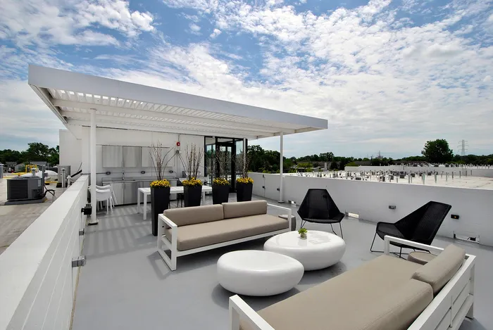 Chic rooftop terrace with modern seating, lush greenery, and expansive views under a clear sky.