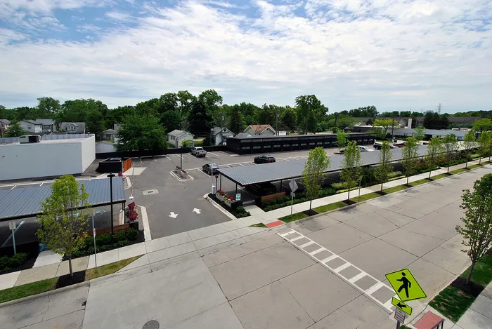 Charming suburban view featuring tree-lined streets, modern parking spaces, and well-maintained sidewalks under a bright, blue sky.