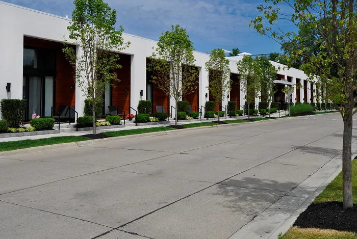 Modern row of stylish townhouses with lush landscaping and inviting patios in an urban setting.