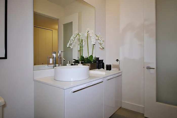 Sleek modern bathroom showcasing a stylish sink with elegant orchid decor and contemporary fixtures.