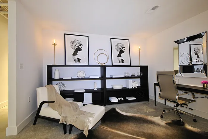 Modern home office with sleek design featuring monochrome art, elegant shelving, and a stylish workspace chair on a polished concrete floor.
