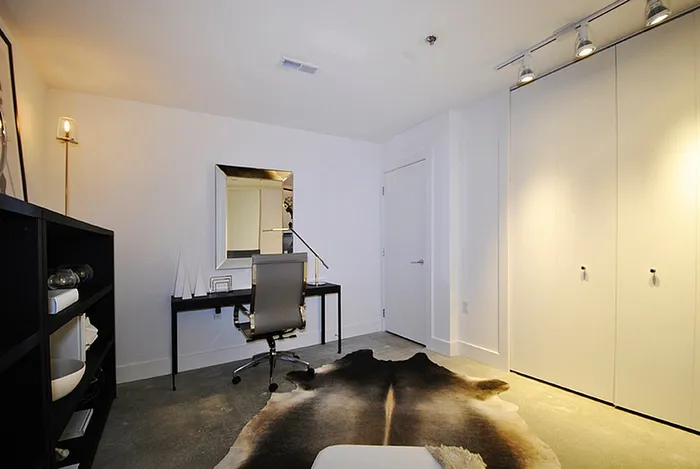 Contemporary home office with sleek desk, modern swivel chair, and stylish cowhide rug in a well-lit room.