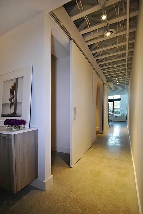 Modern hallway with exposed ceiling, sleek concrete floors, and contemporary decor.