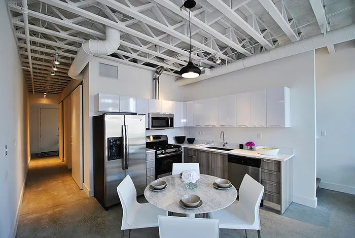 Sleek modern kitchen with stainless steel appliances, chic pendant lighting, and a stylish dining area.