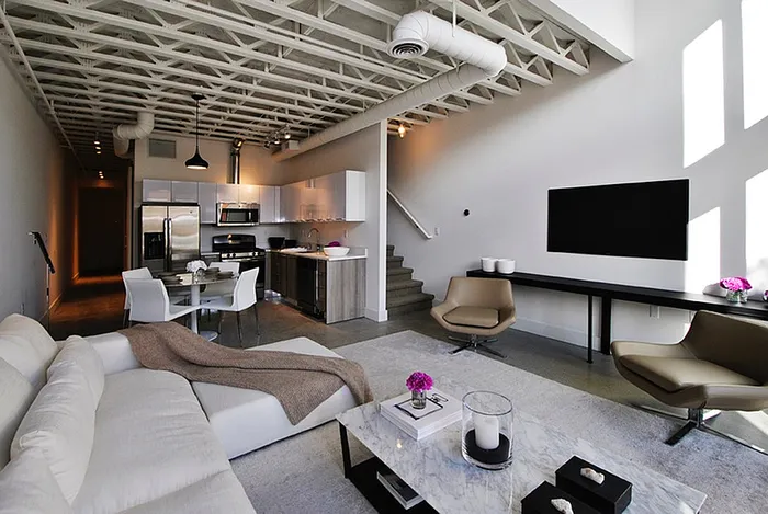 Modern loft-style living area with sleek open-concept design, featuring a comfortable lounge space, elegant kitchen, and dining area with chic decor.