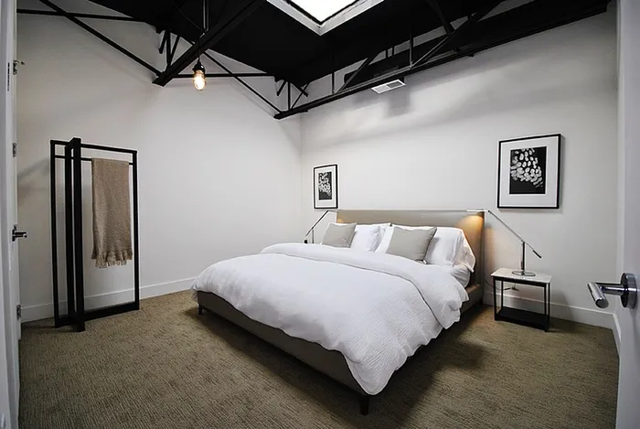 Chic modern bedroom with a plush bed, stylish lighting, and elegant decor, perfect for relaxation.