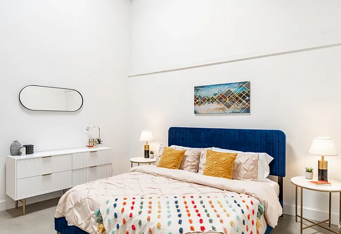 Chic bedroom featuring a plush blue velvet headboard, stylish decor, and elegant lighting for a cozy ambiance.