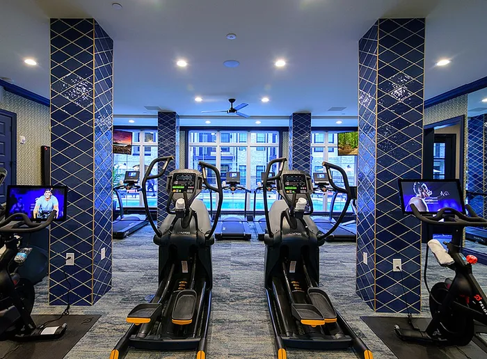 Modern fitness center with state-of-the-art treadmills, vibrant blue accents, and a pool view, perfect for an energizing workout.