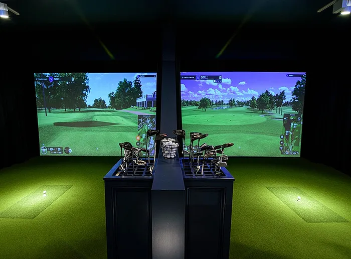 Luxury apartment featuring a state-of-the-art indoor golf simulator with vibrant greens and cutting-edge technology, perfect for golfers.