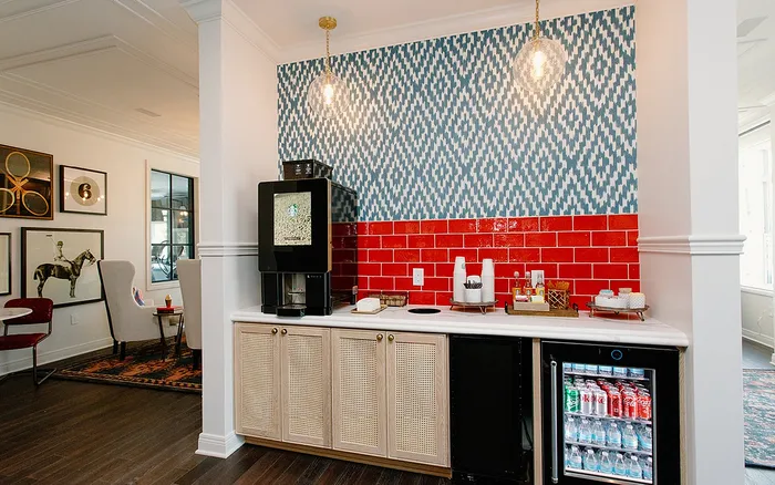 Chic apartment corner with a vibrant red-tiled backsplash and patterned wallpaper, featuring a modern coffee machine and mini bar area for ultimate relaxation.