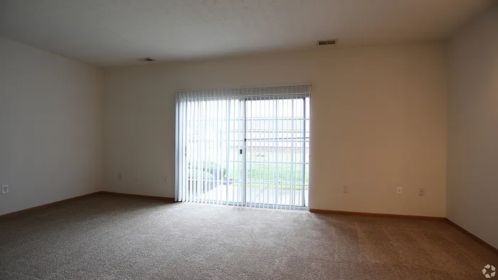 Bright, spacious living area with large windows and plush carpeting, perfect for natural light lovers.
