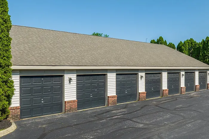 Modern multi-car garage facility with sleek black doors, situated amidst lush green landscaping.